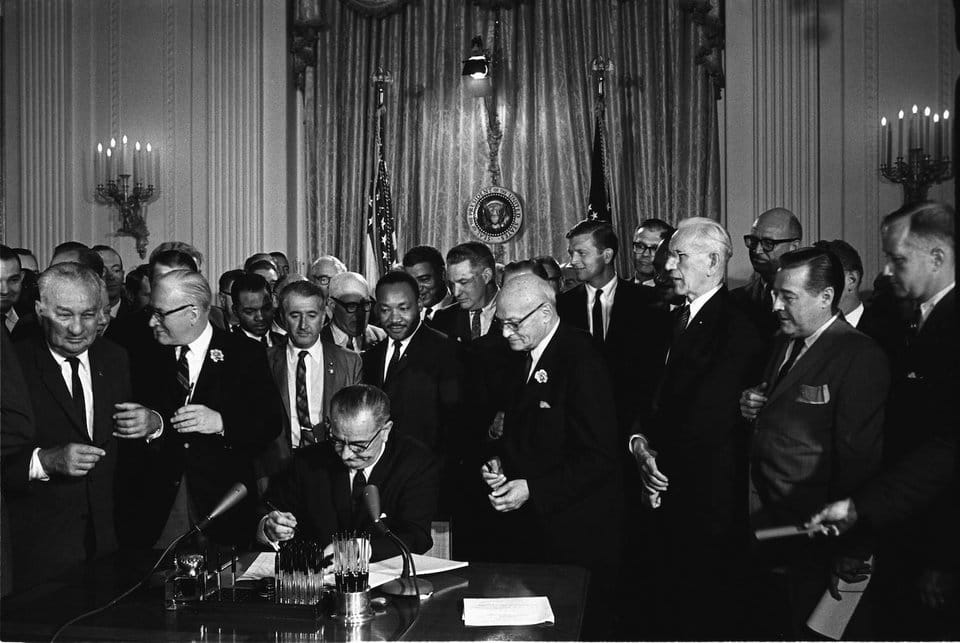 King stands behind President Lyndon B. Johnson as he signs the Civil Rights Act of 1964. - Expert Advice