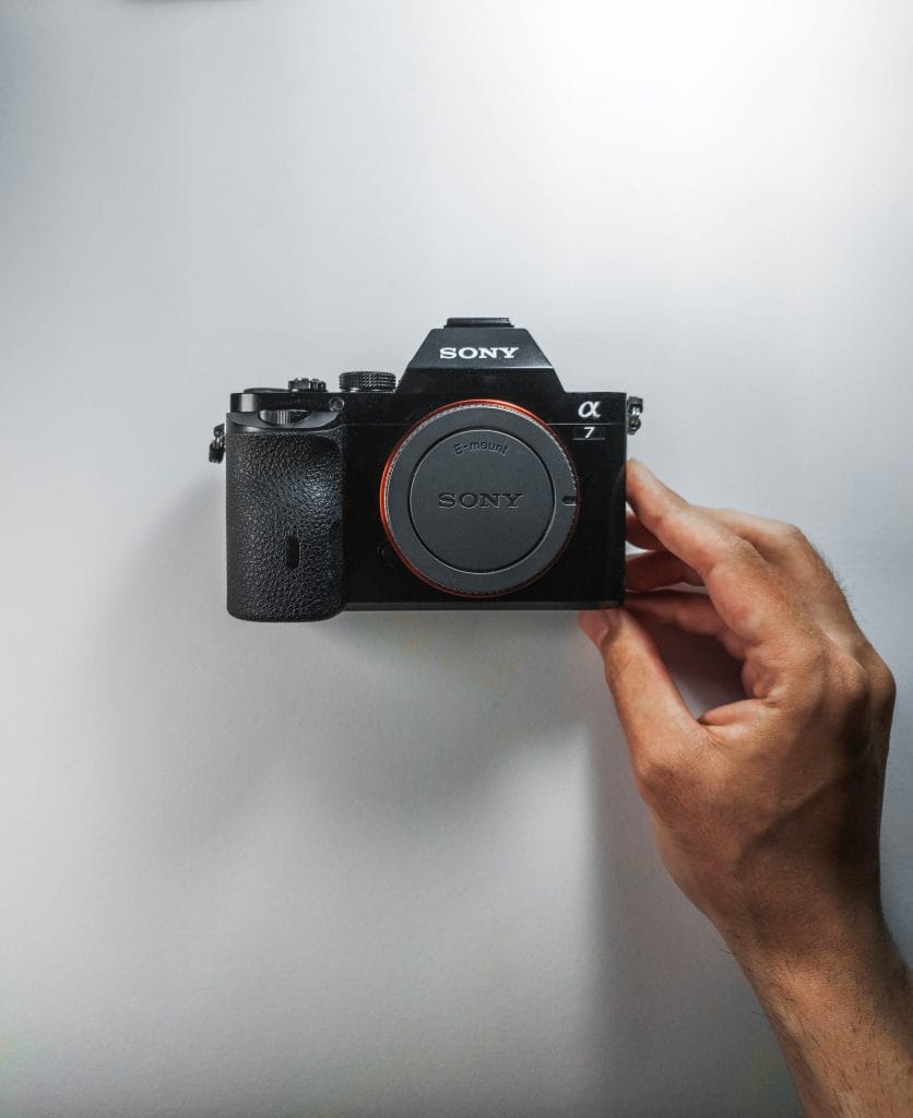 Sony a7 - Expert Advice Hand holding a Sony A7 mirrorless camera in front of a white surface