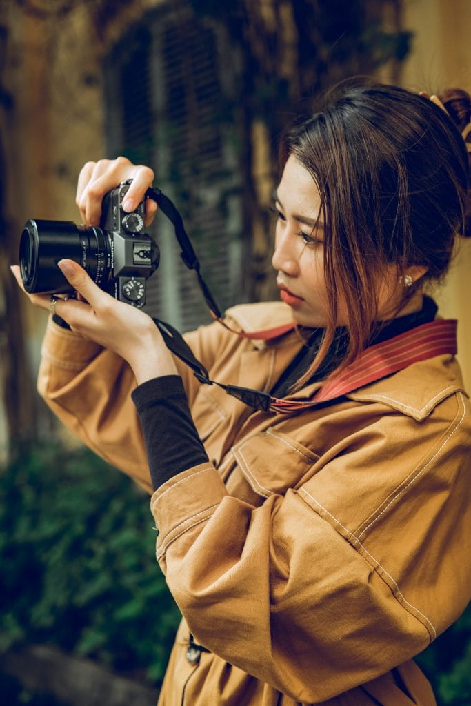 pexels-kha-ruxury-11791288 - Expert Advice Young woman in a trenchcoat shooting a mirrorless camera.