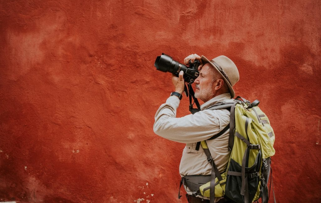 - Expert Advice Man with backpack on taking picture with wildlife photography camera.