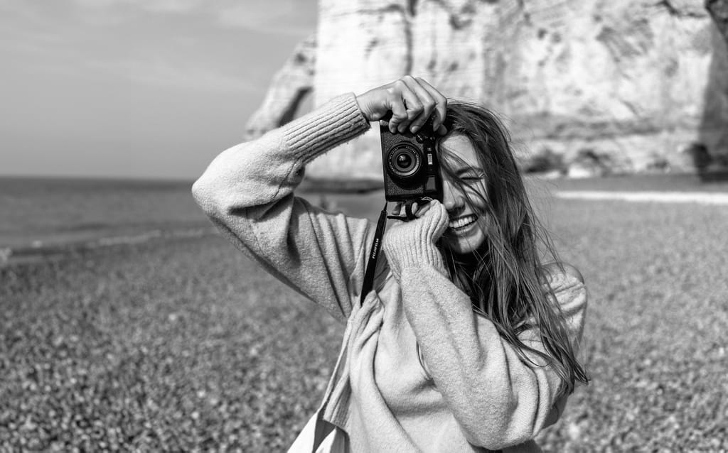 girl holding a camera on the beach